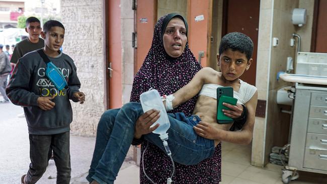A Palestinian woman carries her injured child at al-Aqsa Martyrs Hospital in Deir el-Balah as Israel continues his airstrikes.Picture: AFP