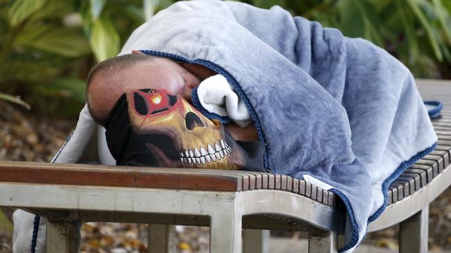 A homeless man sleeps on a park bench at the Cairns Esplanade lagoon.