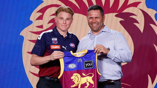 MELBOURNE, AUSTRALIA - NOVEMBER 20: The number five pick, Levi Ashcroft is presented his Brisbane jumper by Chris Johnson during the 2024 Telstra AFL Draft at Marvel Stadium on November 20, 2024 in Melbourne, Australia. (Photo by Michael Willson/AFL Photos via Getty Images)