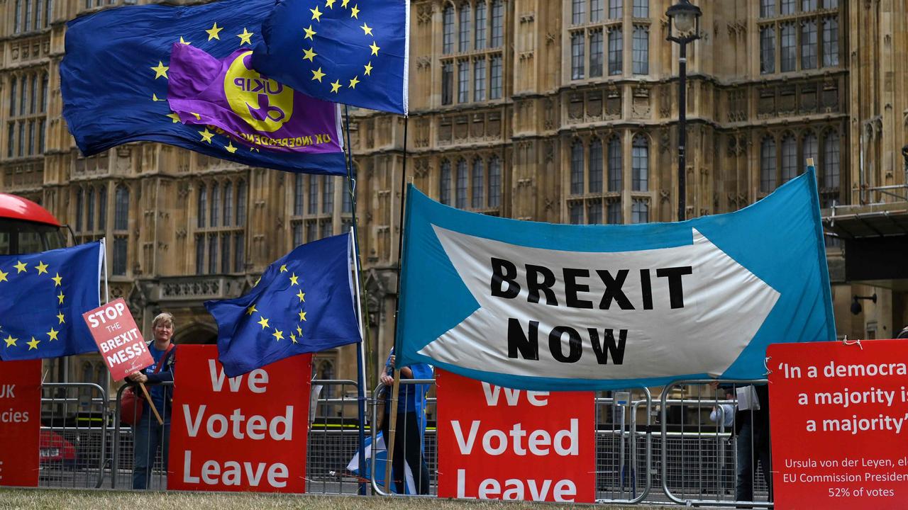 The EU flags of anti-Brexit activists fly as pro-Brexit activists stand with their placards and demonstrate near the Houses of Parliament in central London. Picture: AFP