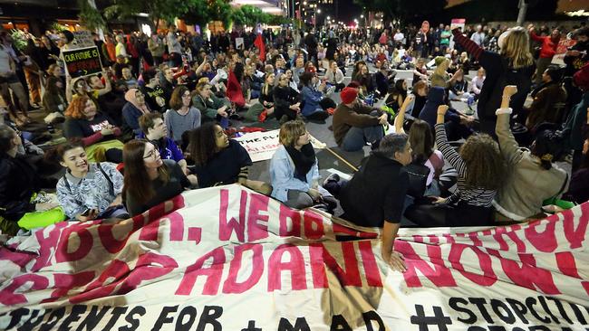 Adani protesters blocked an intersection in the cultural precinct of Brisbane on Friday evening. Three of them glued their hands to the road. Picture: AAP Image/Richard Gosling