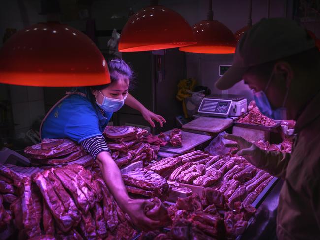 A Chinese meat vendor wears a protective mask as she serves a customer at her stall at a food market in Beijing, China. Picture: Getty