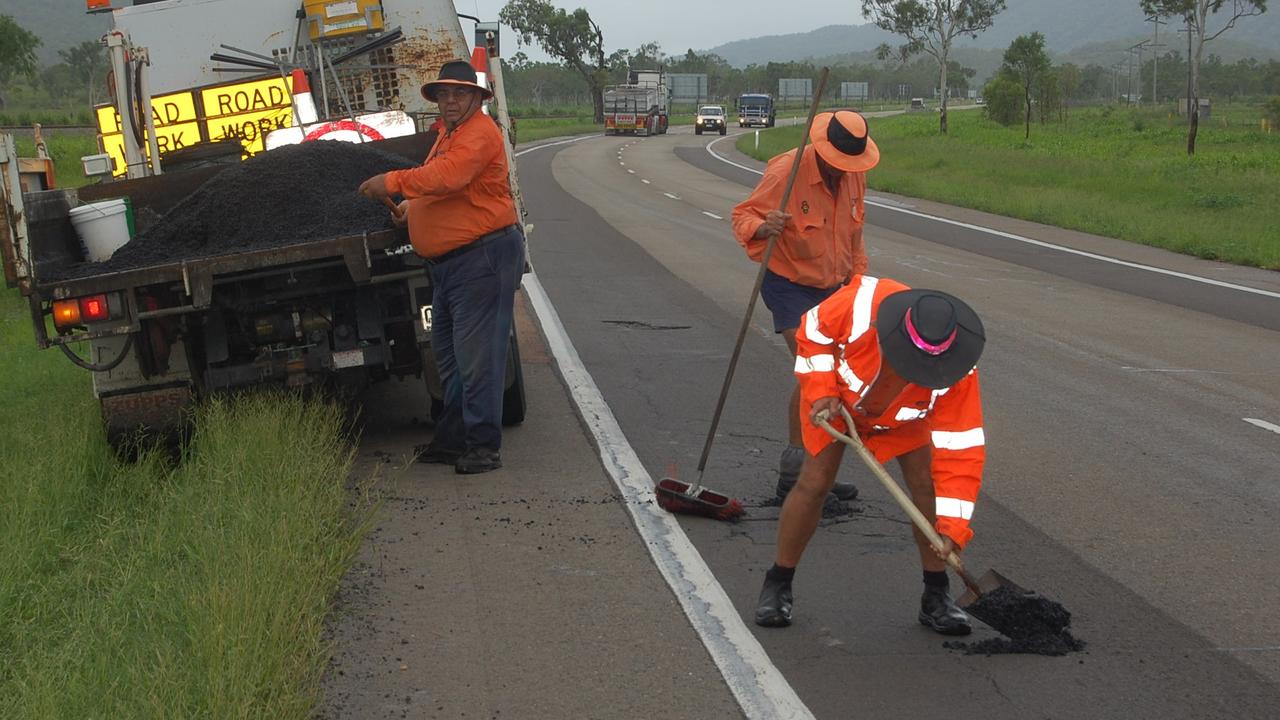 Roadworkers filling in potholes in drizzly conditions on the Bruce Highway south of Townsville.