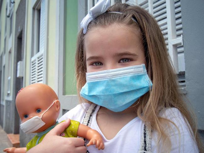 Naidelin, 5, and her doll pose wearing a face mask in the street in Santa Cruz on the Canary Island of Tenerife, on April 26, 2020 during a national lockdown to prevent the spread of the COVID-19 disease. - After six weeks stuck at home, Spain's children were being allowed out today to run, play or go for a walk as the government eased one of the world's toughest coronavirus lockdowns. Spain is one of the hardest hit countries, with a death toll running a more than 23,000 to put it behind only the United States and Italy despite stringent restrictions imposed from March 14, including keeping all children indoors. Today, with their scooters, tricycles or in prams, the children accompanied by their parents came out onto largely deserted streets. (Photo by DESIREE MARTIN / AFP)