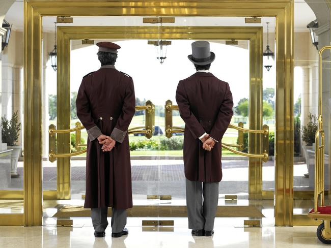 Generic image of a concierge and bellboy standing at a hotel entrance.