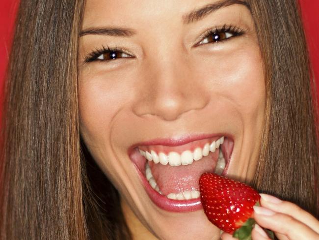 Woman eating strawberries. Thinkstock.