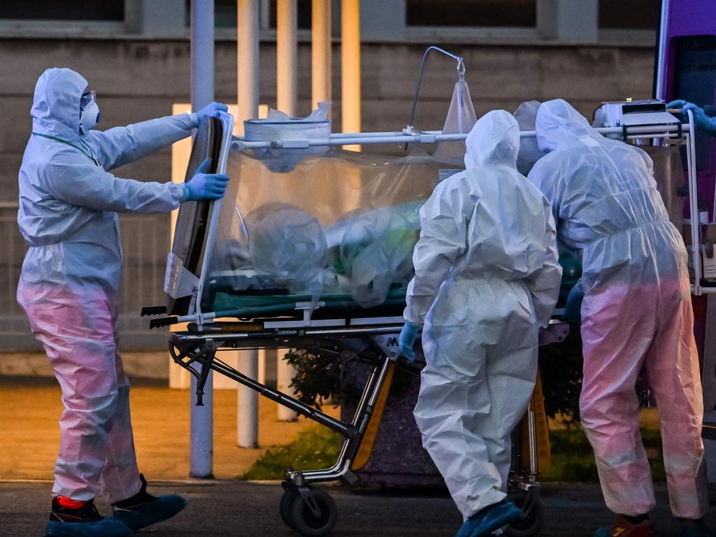 Medical workers in overalls stretch a patient under intensive care into the newly built Columbus Covid 2 temporary hospital in Rome. Picture: ANDREAS SOLARO / AFP
