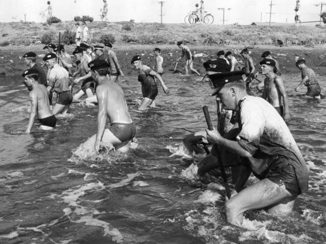 1966: Cadets from the Fort Largs Police Academy wade through mud and water at Patawalonga Boat Haven during the search for the Beaumont children — Jane, nine, Arnna, seven, and Grant, four — who disappeared from Glenelg Beach on January 26. The South Australian case remains unsolved to this day.