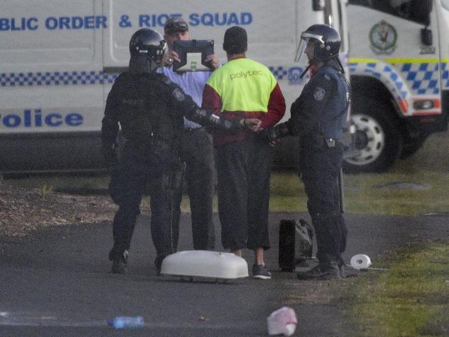 Riot police lead a detainee away in handcuffs during a riot at the Frank Baxter Juvenile Justice Centre, Kariong. (AAP Image/Bianca De Marchi)