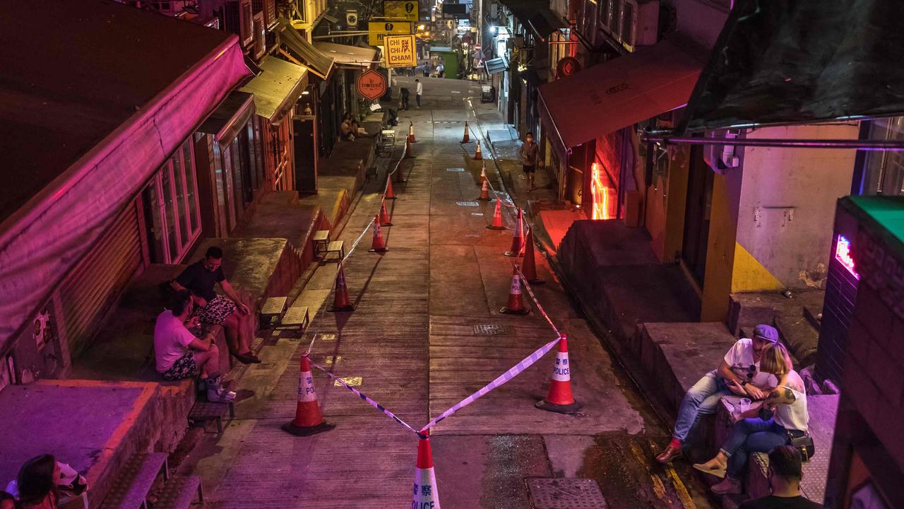 People sitting on a street cordoned off by police with bars and restaurants closed due to Covid-19 coronavirus restrictions in Hong Kong. (Photo by DALE DE LA REY / AFP)