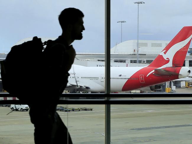 SYDNEY, AUSTRALIA - MARCH 10: A passenger walks past a Qantas jet at the International terminal at Sydney Airport on March 10, 2020 in Sydney, Australia. Qantas has cut almost a quarter of its international capacity for the next six months as travel demands fall due to fears over COVID-19. The airline today announced it was altering routes to London and would be parking eight of their 12 A380 aircraft. (Photo by Mark Evans/Getty Images)