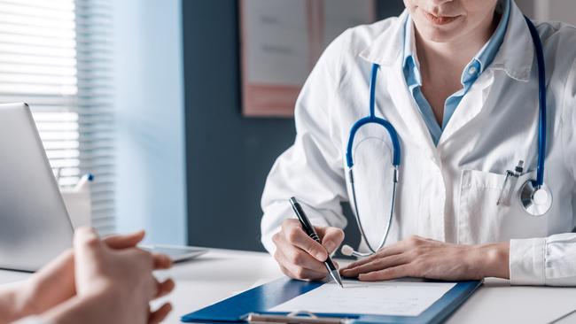 Doctor sitting at desk and writing a prescription for her patient