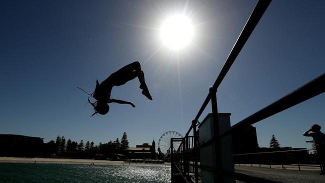 A girl backflips off the jetty at Glenelg Beach on Thursday, January 24, 2019, the hottest Adelaide day on record. Photo: AAP Image/Kelly Barnes.