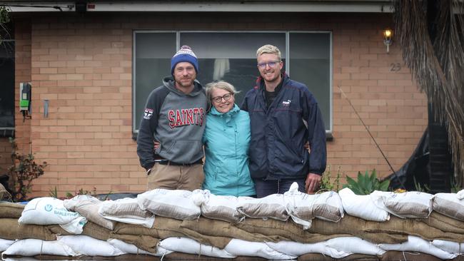 Natalie Murphy with her brother Dallas (left) and son Riley have been fighting the flood water out of her father’s house. Picture: David Caird