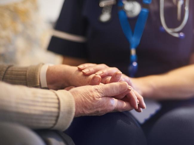 A female nurse consoles a senior patient at home, aged care generic