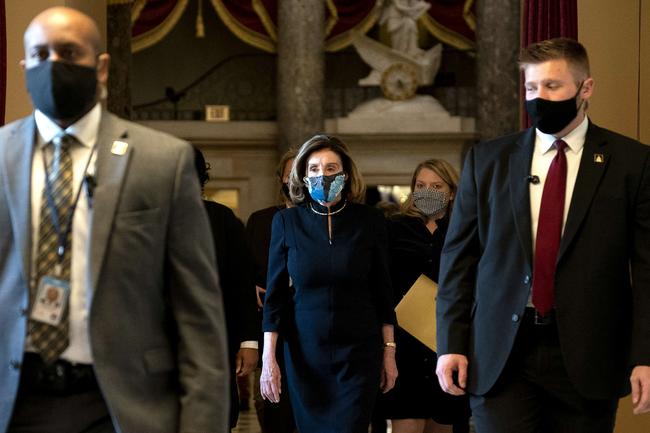 WASHINGTON, DC - JANUARY 13: Speaker of the House Nancy Pelosi (D-CA) (C) wears a protective mask while walking to the House Floor during a vote on the impeachment of President Donald Trump at the U.S. Capitol on January 13, 2021 in Washington, DC. The House of Representatives moved forward with impeachment following Vice President Mike Pences refusal to use the 25th amendment to remove Trump from office after protestors breached the U.S. Capitol last week. Stefani Reynolds/Getty Images/AFP