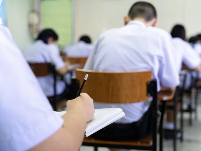 Soft focus.high school or university student holding a pencil writing on a paper answer sheet sitting on a chair lecturing on the final exam participating in an exam room or classroom students in uniform.  Picture: istock