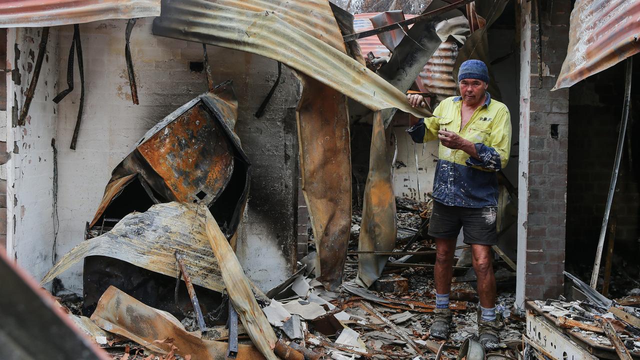 Ash Buchanan walking through the remains of his family home, wiped out by the New Year’s Eve fires. Picture: Gaye Gerard