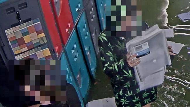 CCTV shared by Emmanuel College, Carrara, appeared to show two teenage girls dumping the contents of student lockers into lapping floodwaters. Picture: Supplied