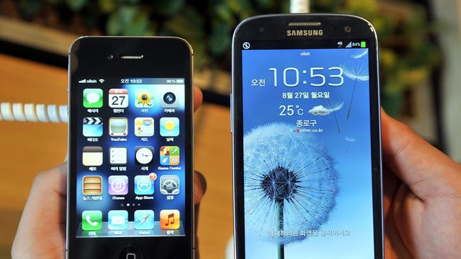 (FILES) This file photo illustration taken on August 27, 2012 shows an employee holding an Apple iPhone 4s (L) and a Samsung Galaxy S3 (R) at a mobile phone shop in Seoul. Arch-rivals Samsung and Apple have decided to drop a series of bitter patent disputes pending in courts outside the United States, the South Korean electronics giant said on August 6, 2014. AFP PHOTO / FILES / JUNG YEON-JE