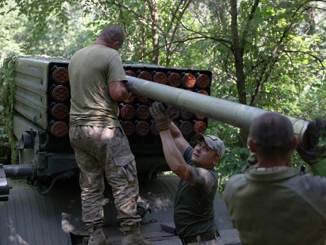 Ukrainian artillerymen load missiles onto a self-propelled 122mm multiple rocket launcher BM-21 