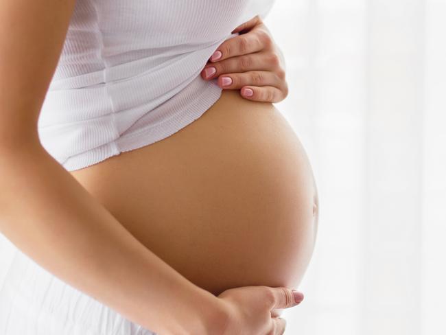 Pregnant woman standing next to window