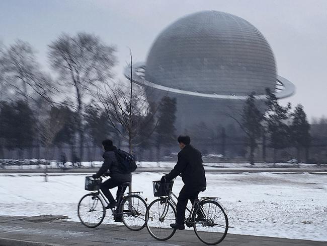 North Koreans cycle past a planetarium at the Three Revolutions Exhibition Hall in Pyongyang, North Korea. Picture:  AP
