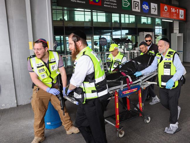 Members of Israeli security and emergency services transport the body of the reported attacker at the site of a stabbing at a central bus station in Haifa. Picture: AFP