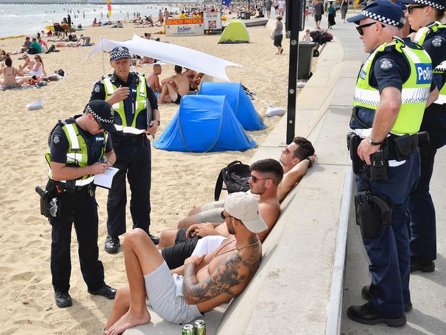 Police issue a fine or warning to some young men for drinking at St Kilda beach. Picture: Jason Edwards