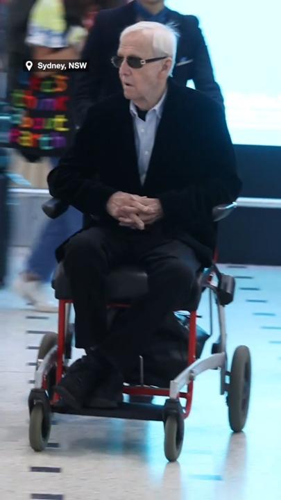 Paul Hogan returns to Australia alone in airport wheelchair