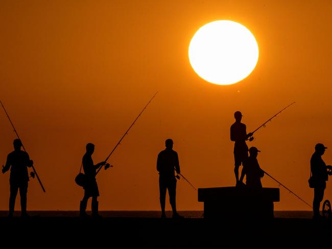 TOPSHOT - People fish at sunset on Havana's Malecon waterfront on July 6, 2023. The planet recorded its hottest day this week, reaching 17.18Â° Celsius. This record had already been broken last Monday. Scientists warn that this situation could be repeated on more occasions during 2023. (Photo by YAMIL LAGE / AFP)