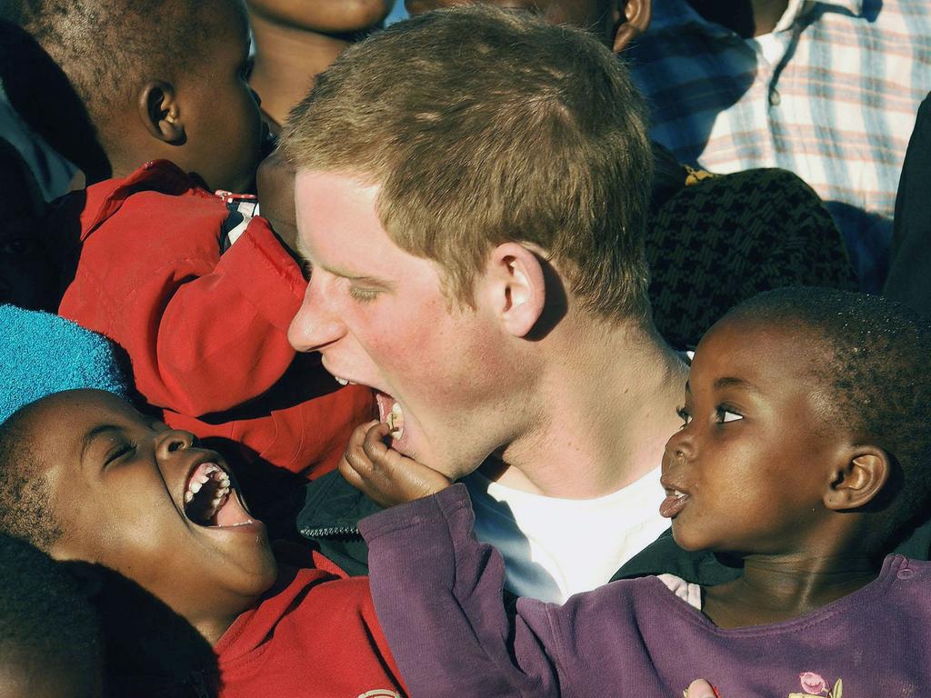 Prince Harry cuddles children Mutsu and Lintle in the grounds of the Mants’ase children’s home, while on a return visit to Lesotho in southern Africa on April 24 2006. Picture: Getty