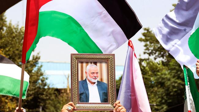 People hold up the Palestinian flag and a portrait of assassinated Hamas chief Ismail Haniyeh Hamas chief during a rally at Tehran University, in the Iranian capital Tehran on July 31, 2024. (Photo by AFP)