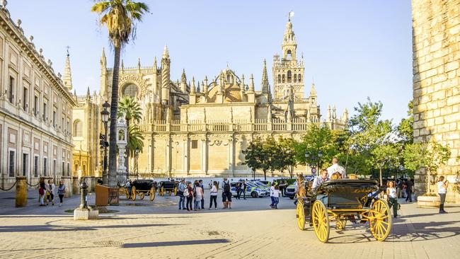 A carriage rolls into the square at Seville Cathedral.