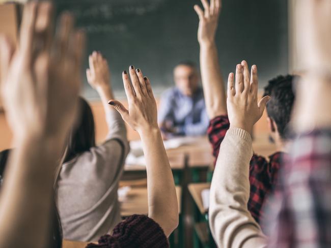 Rear view of group of students raising hands to answer teacher's question in the classroom. Focus is on hands in the middle.Picture: iStock