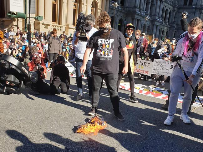 A protester sets the Australian flag on fire at a Black Lives Matter rally in Brisbane.