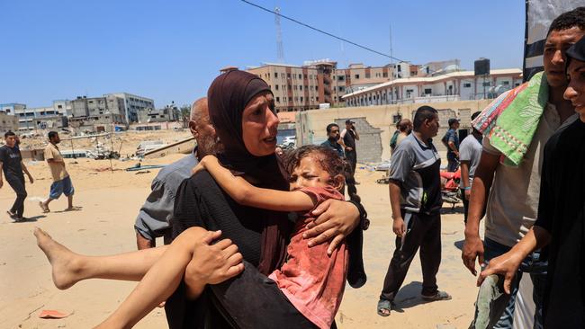 A Palestinian woman carries an injured child to the Nasser hospital in Khan Yunis after the airstrike. Picture: AFP