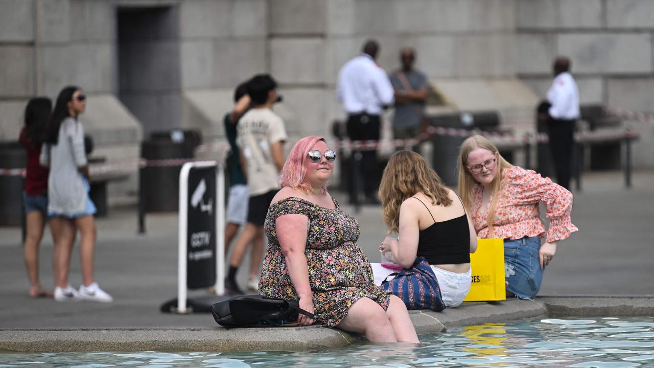 Pedestrians cool off with their feet in the water of the Trafalgar Square fountain, in central London. Picture: AFP