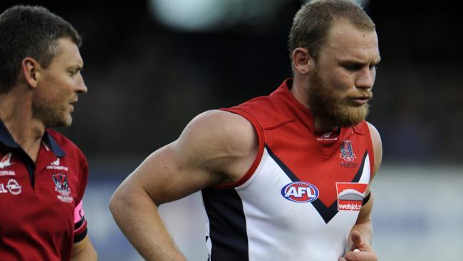  Melbourne's Dean Terlich in the hands of trainers after copping a knock to the ribs against Fremantle. 