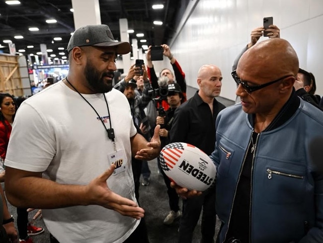 Dwayne 'The Rock' Johnson (right) holding a rugby league football with Australian NFL star Jordan Mailata. Credit: Supplied