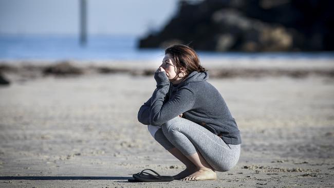 An onlooker waits on the beach as police divers recover the body of the teenage girl. Picture: AAP/Mike Burton