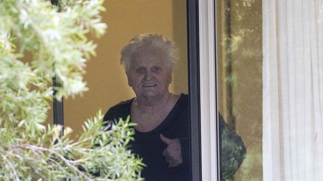 Patricia Shea, 76, who is COVID-19-positive, gives a thumbs-up to her son at Newmarch House in Sydney on Sunday. Picture: Damian Shaw