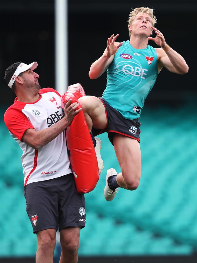 Cox helps Isaac Heeney practice his hangers at a training session. Picture: Phil Hillyard