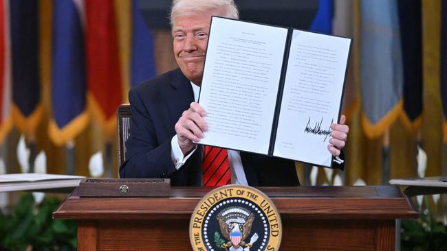 Donald Trump holds up an executive order shutting down the Department of Education. Picture: AFP.