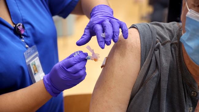 Lalain Reyeg administers a Covid-19 booster vaccine and an influenza vaccine to Army veteran Gary Nasakaitis in Illinois. Picture: Getty Images/AFP