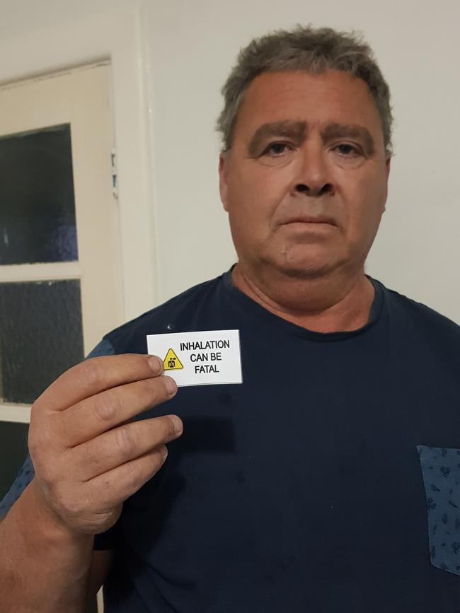 Port Lincoln father Adrian Ryan with the self-made labels warning sniffing LPG gas can kill you.