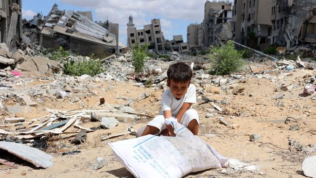 A Palestinian boy plays with sand in front of buildings heavily damaged from an Israeli bombing, in Beit Lahia in the northern Gaza Strip.