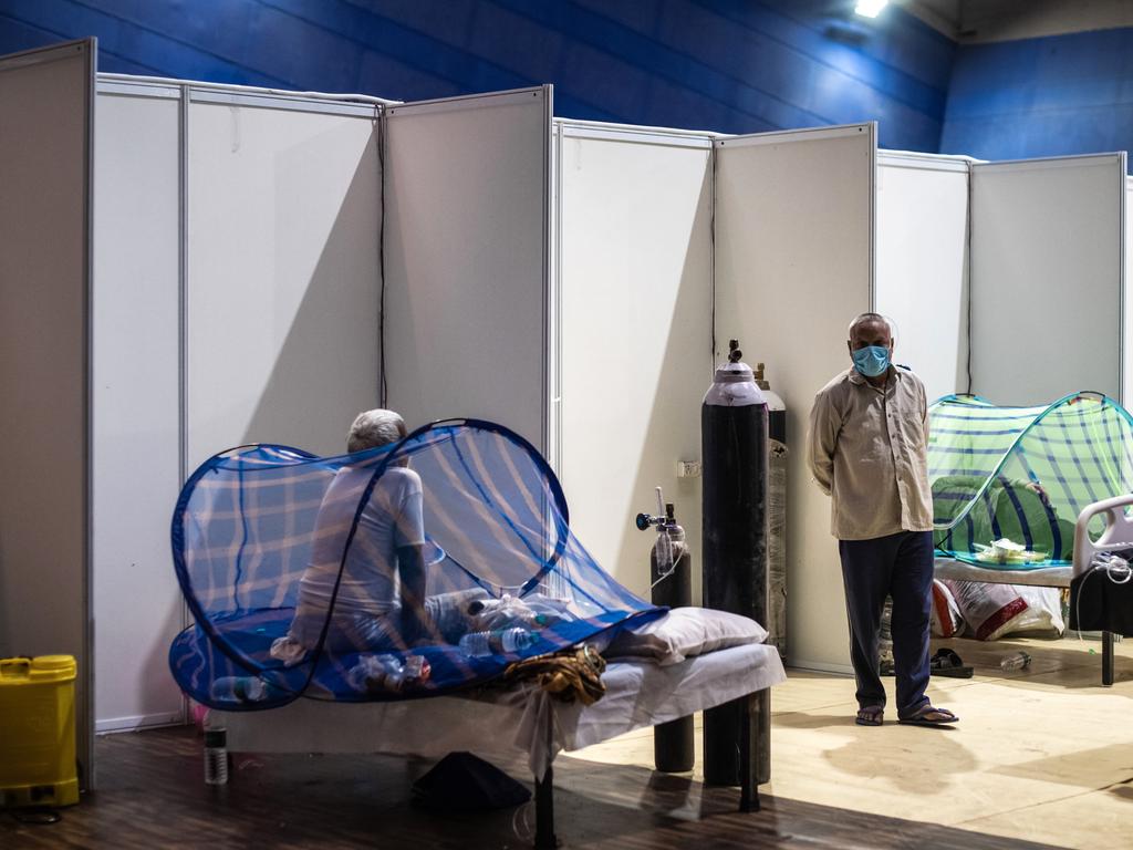 A patient sits on a bed inside a makeshift covid care facility in a sports stadium at the Commonwealth Games Village in New Delhi. (Photo by Getty Images/Getty Images)