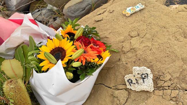 The Dicky Beach surfing community is reeling after the body of a young woman washed ashore. Flowers have been left at the botom of the staircase in her remembrance.