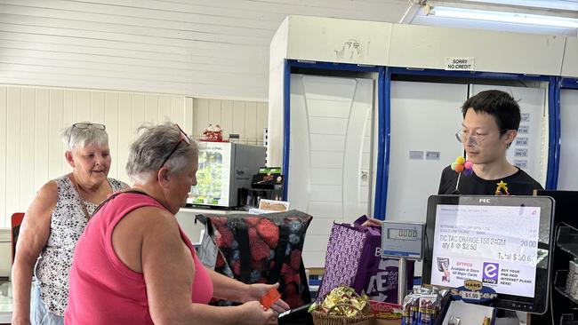 Miriam Vale general store 'The Shop' owner Angus Xu serving Bororen residents Lisa Toombs and Heidi Peters on Sunday morning - two days (August 30 2024) - after a truck and ute fatal crash where ammonium nitrate in one of the tanks of the truck exploded and left a crater on the side of the Bruce Hwy.